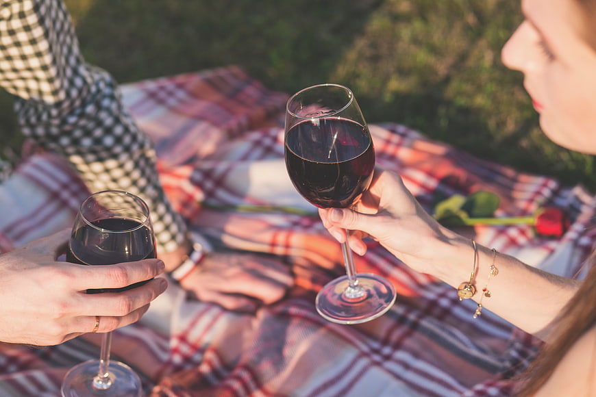 Couple toasting with red wine glasses at a romantic picnic