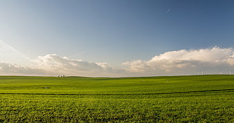 Vibrant Green Rolling Hills with Wind Turbines and Blue Sky