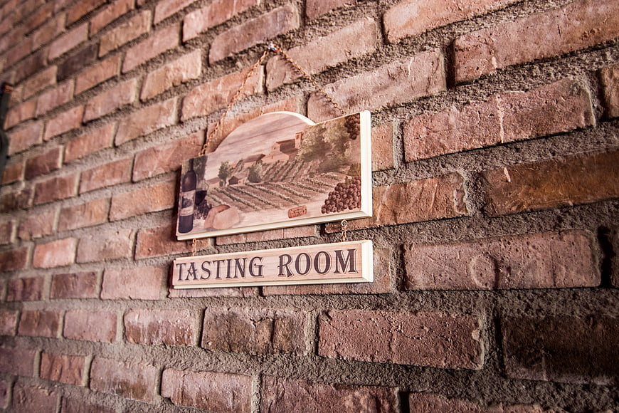 Rustic wooden tasting room sign on brick wall