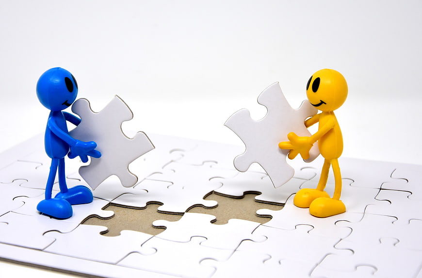 Blue and yellow figures holding puzzle pieces over a gap