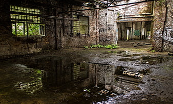 Abandoned industrial factory interior with puddle reflections