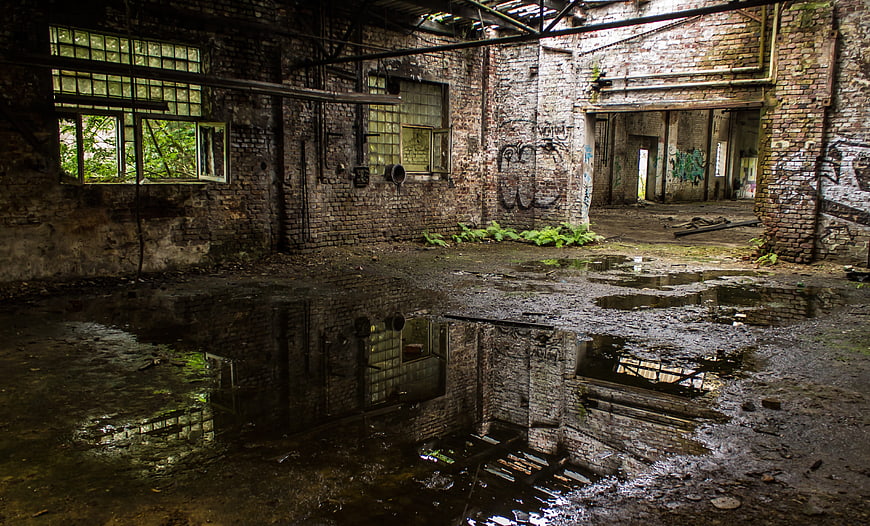 Abandoned industrial factory interior with puddle reflections