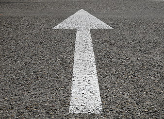 White directional arrow painted on gray asphalt road surface