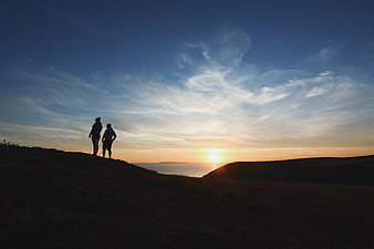 Silhouette of Couple Watching Sunset Over Ocean Cliffs
