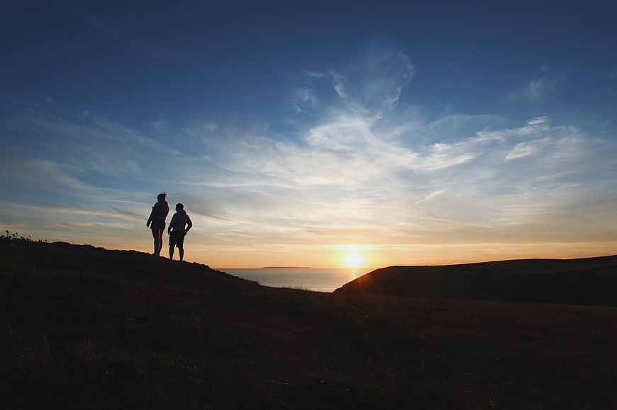Silhouette of Couple Watching Sunset Over Ocean Cliffs