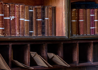 Antique leather-bound books on wooden shelf with letters