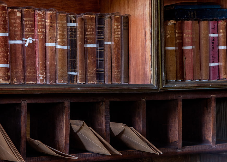 Antique leather-bound books on wooden shelf with letters