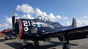 Blue vintage propeller plane on tarmac with sponsor logos