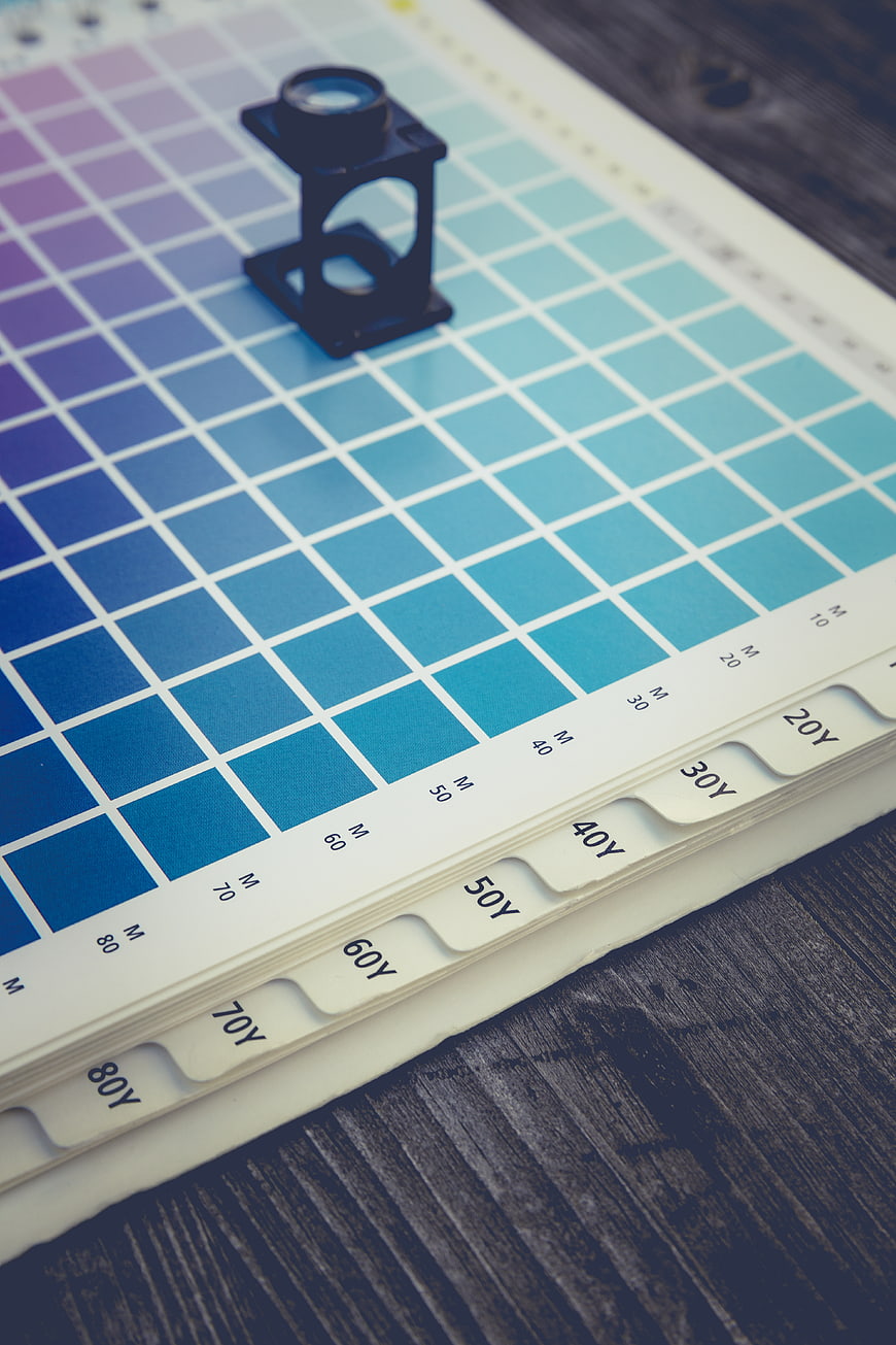 Color swatch book with magnifying glass on wooden table