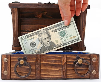 Hand placing twenty dollar bill in wooden treasure chest