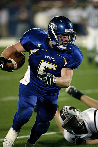 American Football Player Running With Ball In Blue Jersey