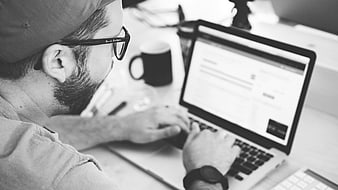 Man Typing on Laptop in Black and White Office Setting