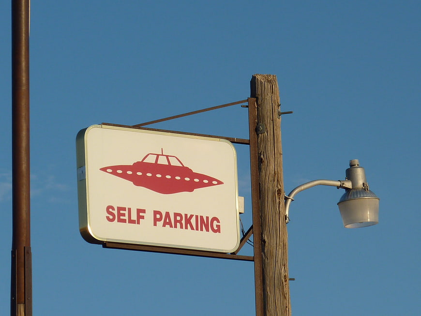 Self Parking UFO Sign on Wooden Pole Against Blue Sky