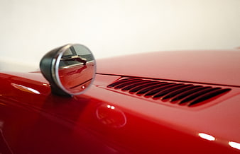 Close-up of red sports car side mirror and hood vent