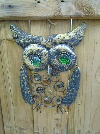 Handcrafted metal owl garden art on wooden fence