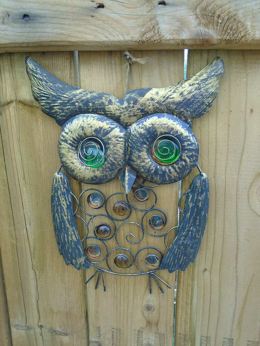 Handcrafted metal owl garden art on wooden fence