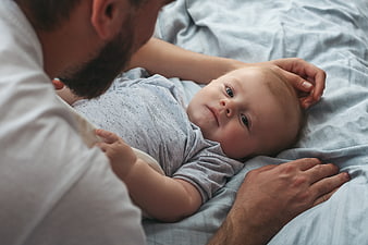 Father Bonding with Newborn Baby on Bed