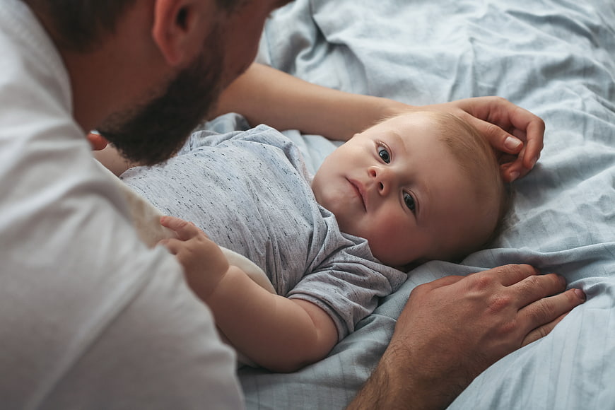 Father Bonding with Newborn Baby on Bed