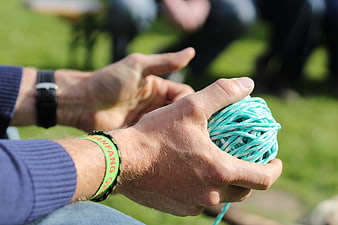 Close-up of hands holding teal yarn ball outdoors