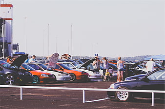 Outdoor car show with modified vehicles and spectators