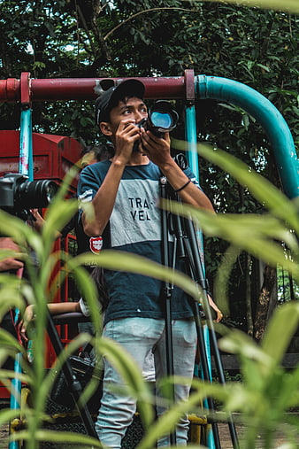 Young man taking photo with DSLR camera in park