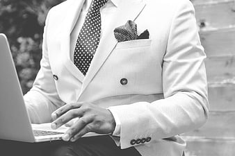 Man in White Suit Typing on Laptop Outdoors