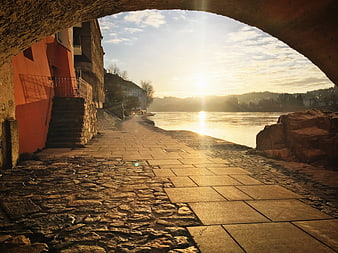 Sunset View Through Stone Arch Over River Walkway