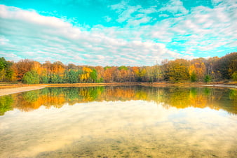 Serene autumn lake with colorful forest reflection and blue sky