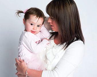 Mother Holding Toddler Daughter In White Studio Portrait