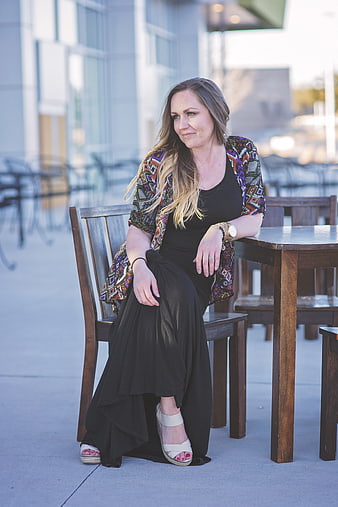 Businesswoman in black dress and patterned jacket sitting at outdoor cafe table