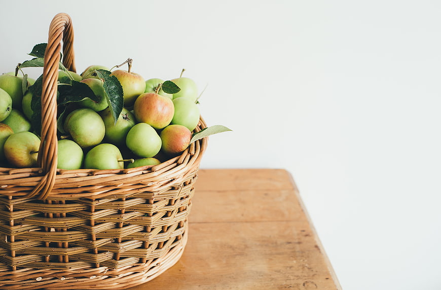 Wicker Basket of Fresh Green Apples on Wooden Table