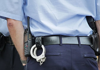 Close-up of police officer uniform with handcuffs and radio