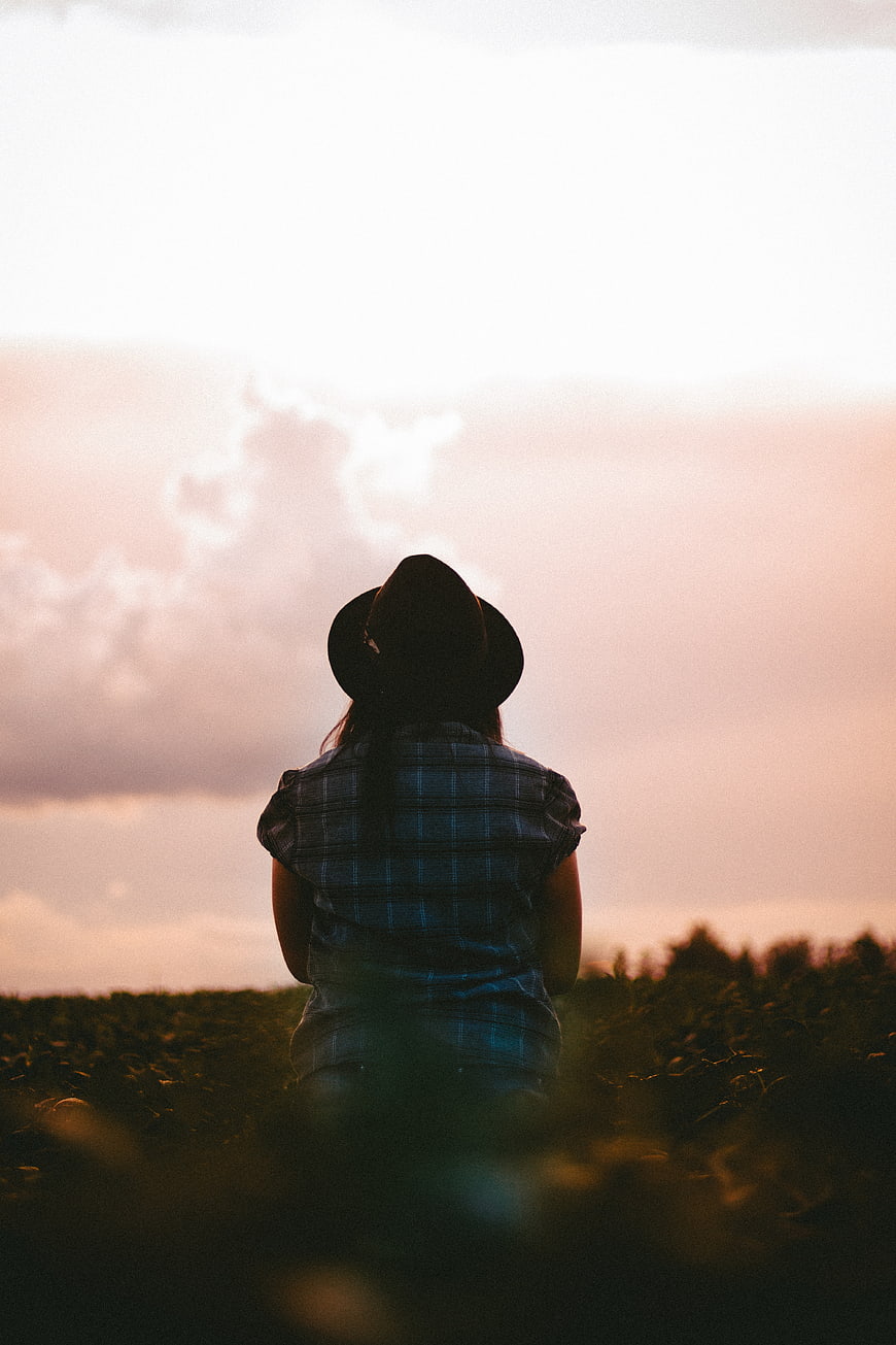 Woman in Hat Watching Sunset Over Field