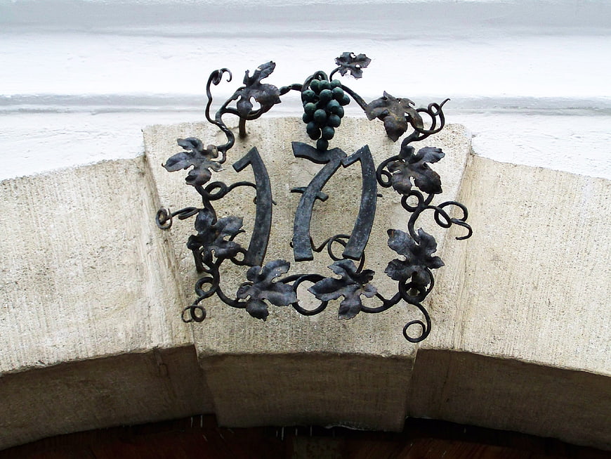 Wrought iron house number 17 with grapevine design on stone