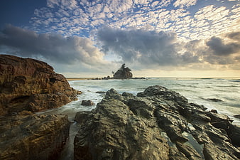 Dramatic Rocky Coastline with Ocean Waves and Cloudy Sky