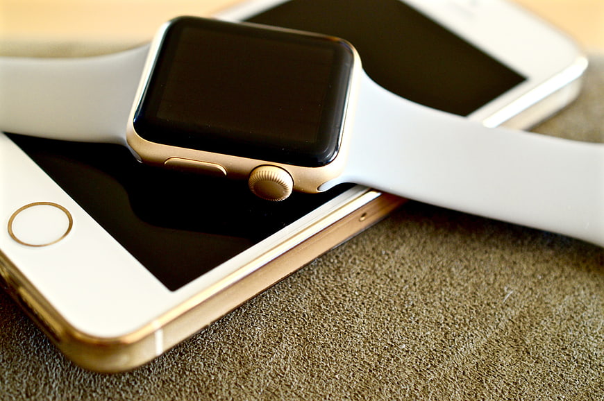 Gold Apple Watch and iPhone on Textured Surface