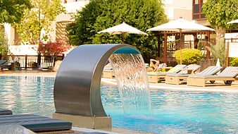 Modern curved water fountain in luxury resort swimming pool