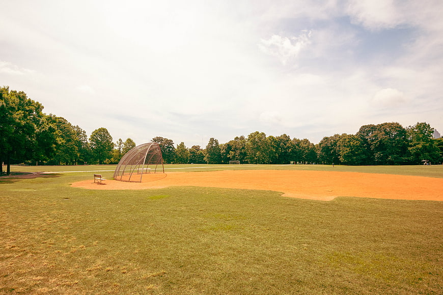 Empty Baseball Field with Batting Cage in Summer Park