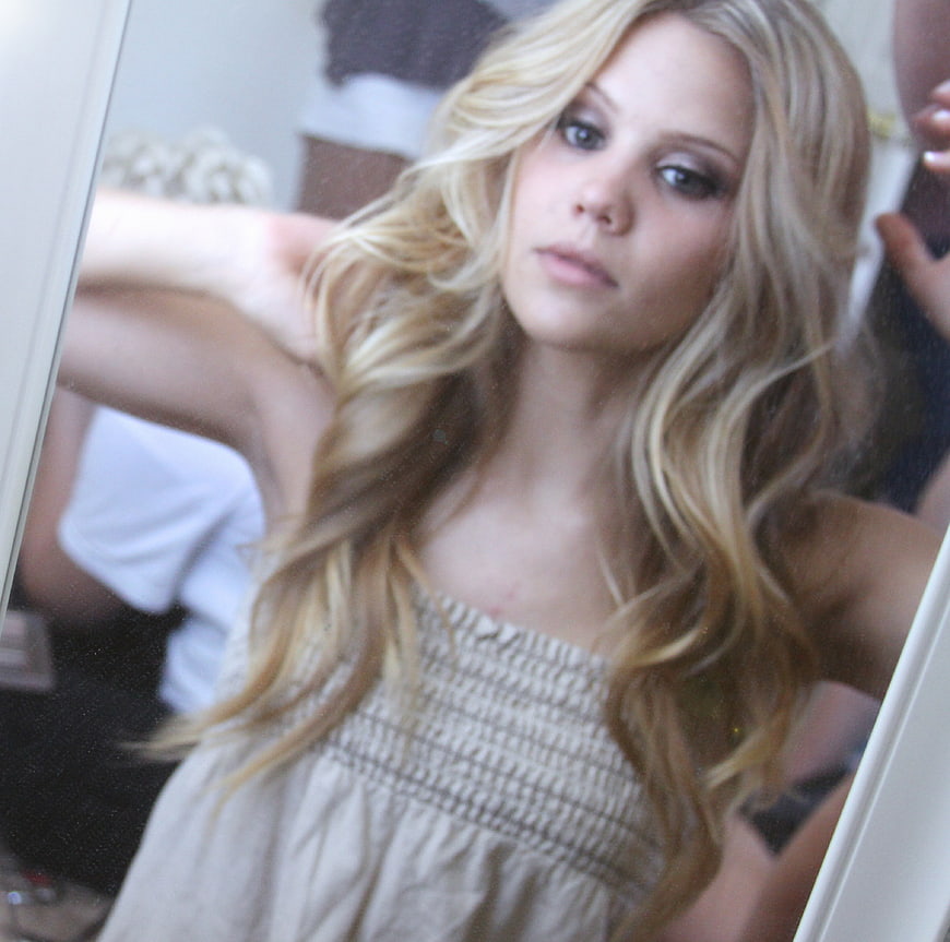Blonde woman taking mirror selfie with wavy hair
