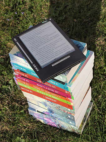 E-reader on stack of books in grass