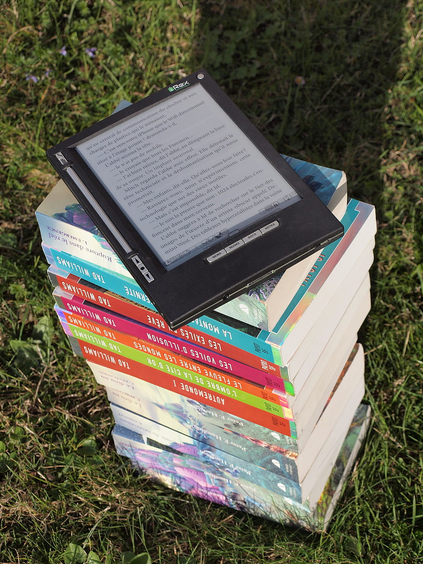 E-reader on stack of books in grass