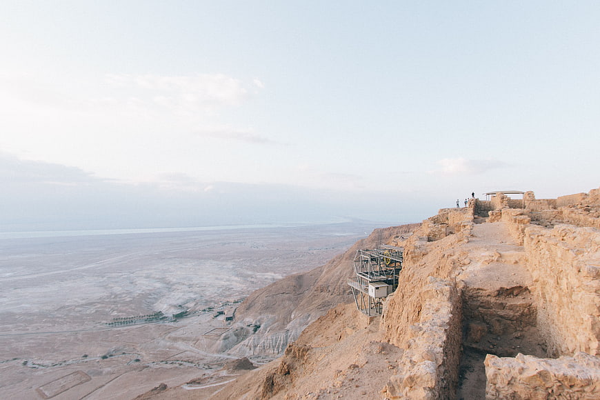 Ancient stone ruins overlooking vast desert valley and distant sea