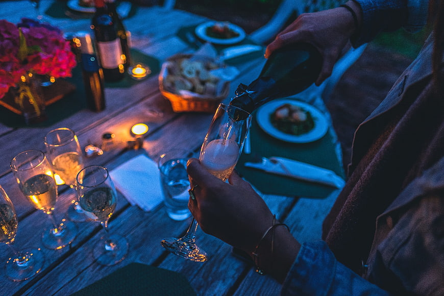 Pouring champagne at a romantic evening dinner table
