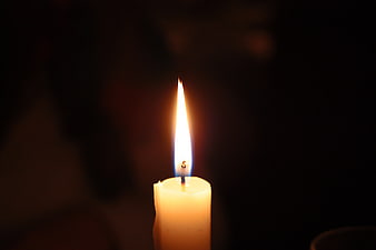 Single lit candle flame in darkness