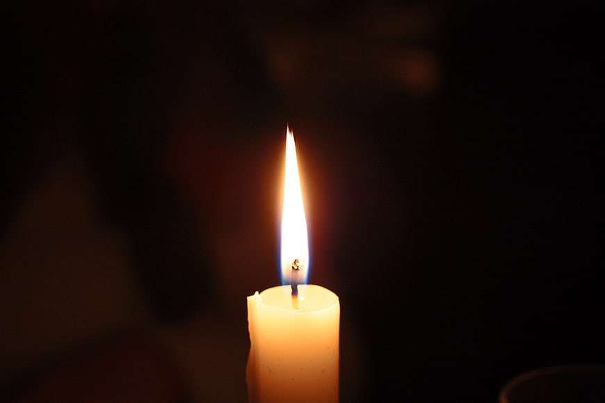Single lit candle flame in darkness