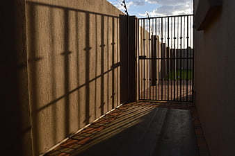 Sunlit alleyway with metal gate and dramatic shadows