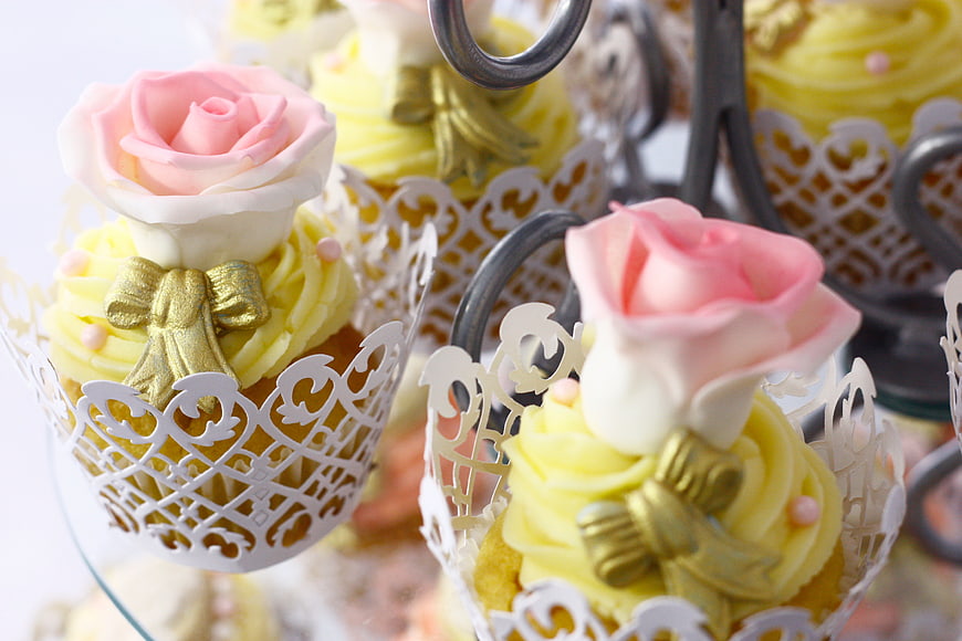 Elegant pink rose cupcakes with gold bows on tiered stand