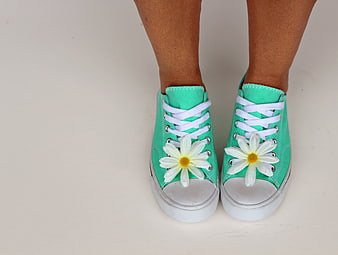 Green sneakers with white daisies on a white background