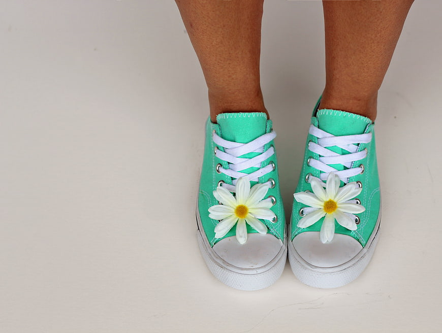Green sneakers with white daisies on a white background