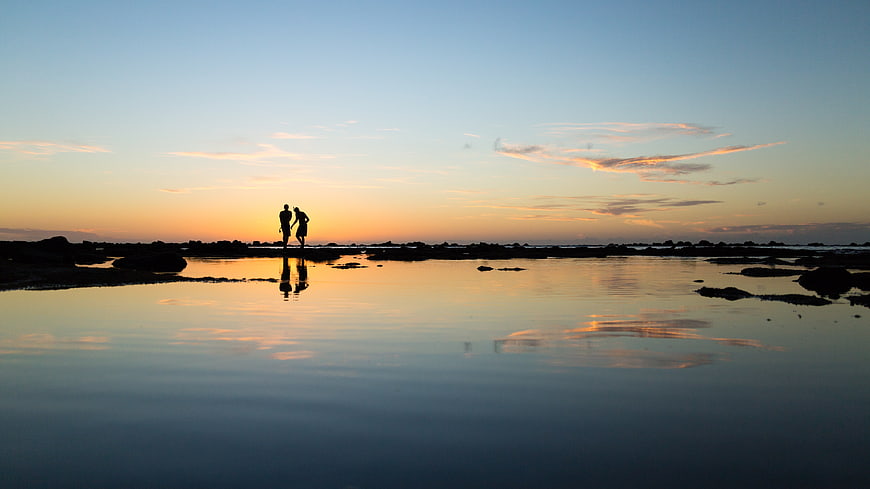 Silhouette of Couple Walking on Beach at Sunset with Reflection